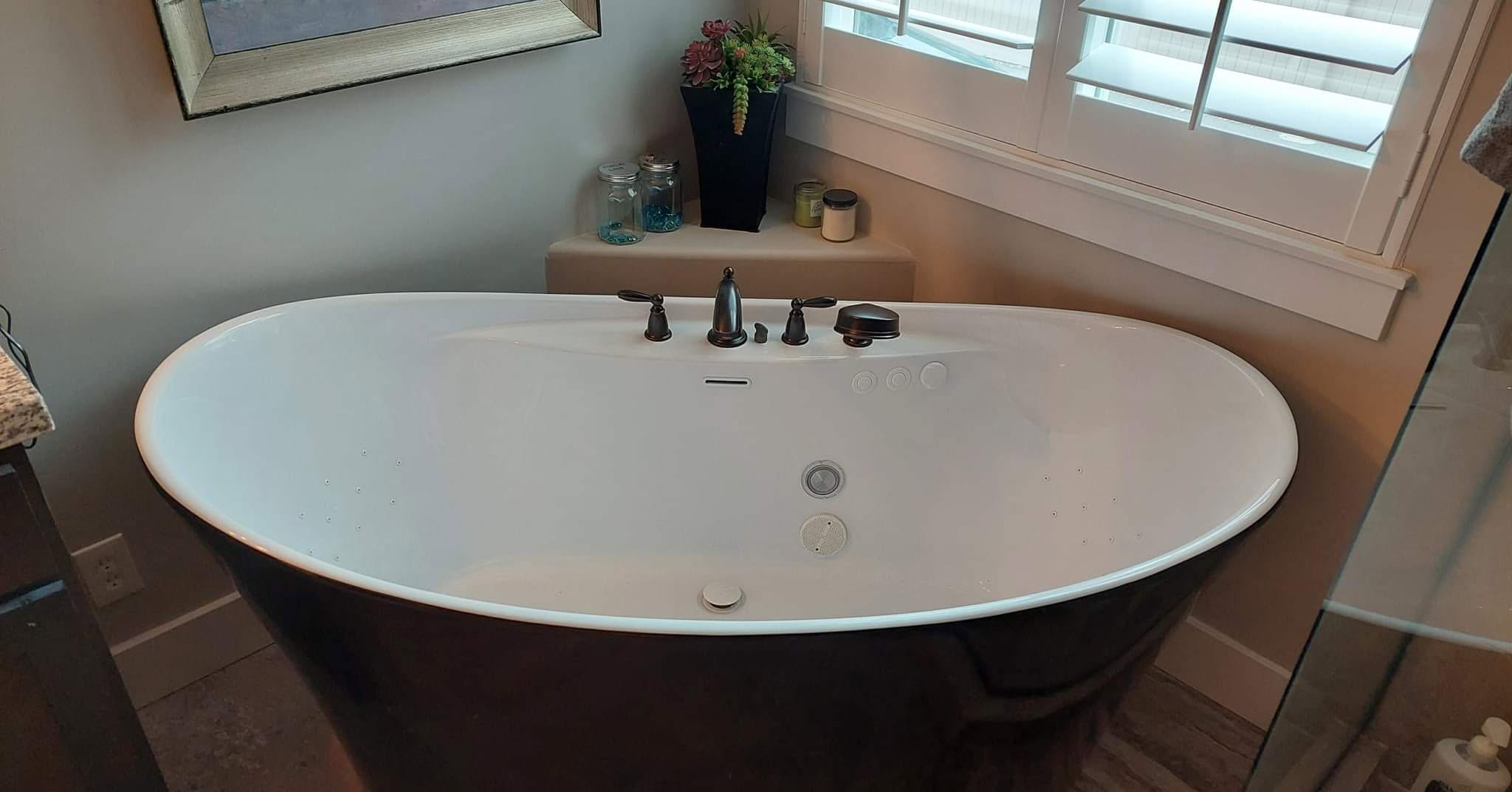 Freestanding tub with dark exterior and finished plumbing fixtures
